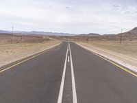 the empty road in the desert with two white lines down the middle of it, as if in the sky