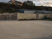 a driveway and driveway entrance with houses in the background with blue sky overhead at sunset