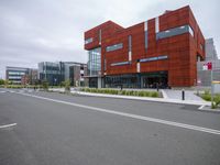 a building with a long parking lane next to it and buildings in the background, as well as many people outside