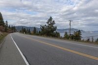 road with yellow lines in the middle and mountains in the background with a few pine trees