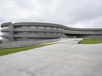 a building with cement roof near green grass and lawn in front of it, under a gray sky