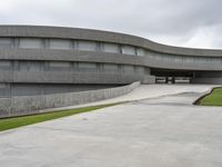 a building with cement roof near green grass and lawn in front of it, under a gray sky