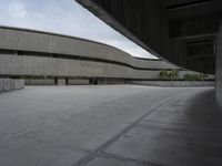 a building with cement roof near green grass and lawn in front of it, under a gray sky