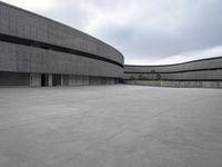 a building with cement roof near green grass and lawn in front of it, under a gray sky