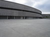 a building with cement roof near green grass and lawn in front of it, under a gray sky