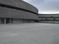 a building with cement roof near green grass and lawn in front of it, under a gray sky