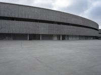 a building with cement roof near green grass and lawn in front of it, under a gray sky