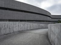 a building with cement roof near green grass and lawn in front of it, under a gray sky