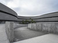 a building with cement roof near green grass and lawn in front of it, under a gray sky