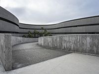 a building with cement roof near green grass and lawn in front of it, under a gray sky