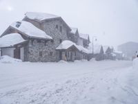 there is snow that is covered up in the street by houses on it with a man standing on a street corner and a car parked in the middle way at the street