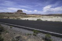 the empty road is going across the mountains in the desert, with mountains and hills