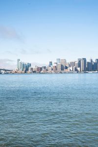 a large body of water surrounded by buildings and a city skyline on a bright day