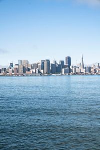 a large body of water surrounded by buildings and a city skyline on a bright day