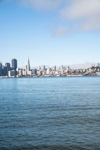 a large body of water surrounded by buildings and a city skyline on a bright day