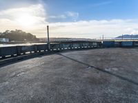 an empty parking lot with stairs, and cars parked beside it in front of a bridge