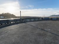 an empty parking lot with stairs, and cars parked beside it in front of a bridge