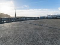 an empty parking lot with stairs, and cars parked beside it in front of a bridge