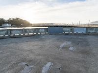 an empty parking lot with stairs, and cars parked beside it in front of a bridge