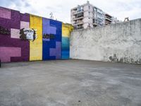 a wall with graffiti depicting a gorilla and a yellow brick in the center and buildings in the background