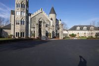 a building with a gothic roof is next to a road and lawn with bushes, shrubs, and bushes