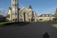 a building with a gothic roof is next to a road and lawn with bushes, shrubs, and bushes