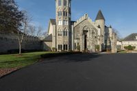 a building with a gothic roof is next to a road and lawn with bushes, shrubs, and bushes