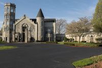 a building with a gothic roof is next to a road and lawn with bushes, shrubs, and bushes