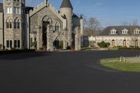 a building with a gothic roof is next to a road and lawn with bushes, shrubs, and bushes