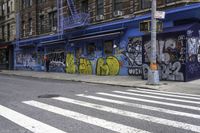 a crosswalk shows no traffic as many graffiti is painted on it's exterior