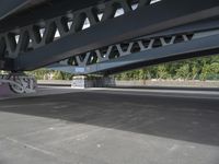 a bike with graffiti is parked underneath a bridge bridged in area where a vehicle is parked