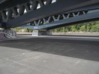 a bike with graffiti is parked underneath a bridge bridged in area where a vehicle is parked