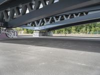 a bike with graffiti is parked underneath a bridge bridged in area where a vehicle is parked