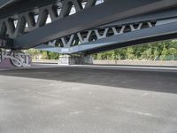 a bike with graffiti is parked underneath a bridge bridged in area where a vehicle is parked