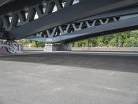 a bike with graffiti is parked underneath a bridge bridged in area where a vehicle is parked