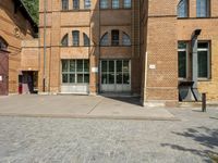 graffiti and bricked walkway outside an old building with open doors and windows at the side