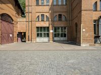 graffiti and bricked walkway outside an old building with open doors and windows at the side