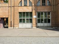 graffiti and bricked walkway outside an old building with open doors and windows at the side