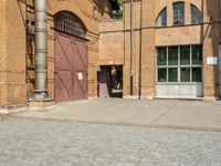 graffiti and bricked walkway outside an old building with open doors and windows at the side