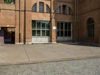 graffiti and bricked walkway outside an old building with open doors and windows at the side