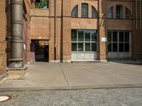 graffiti and bricked walkway outside an old building with open doors and windows at the side