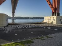 a long bridge spanning over water with graffiti painted across it and a sidewalk in between