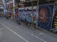 graffiti is seen on this narrow city street lined with parked bikes and buildings along one side