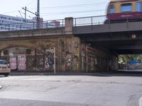 the brick building is covered in graffiti and posters and signs of various names on the side of the street