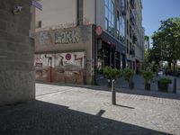 the building is covered with graffiti and signs on the outside of the building it is next to a sidewalk with no cars