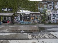 a graffiti covered building in front of some water and green leaves on it's walls