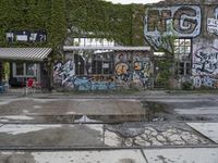 a graffiti covered building in front of some water and green leaves on it's walls