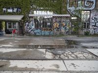 a graffiti covered building in front of some water and green leaves on it's walls