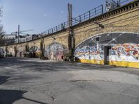 a building covered with lots of different graffiti paint on it's exterior wall next to a brick road