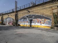 a building covered with lots of different graffiti paint on it's exterior wall next to a brick road